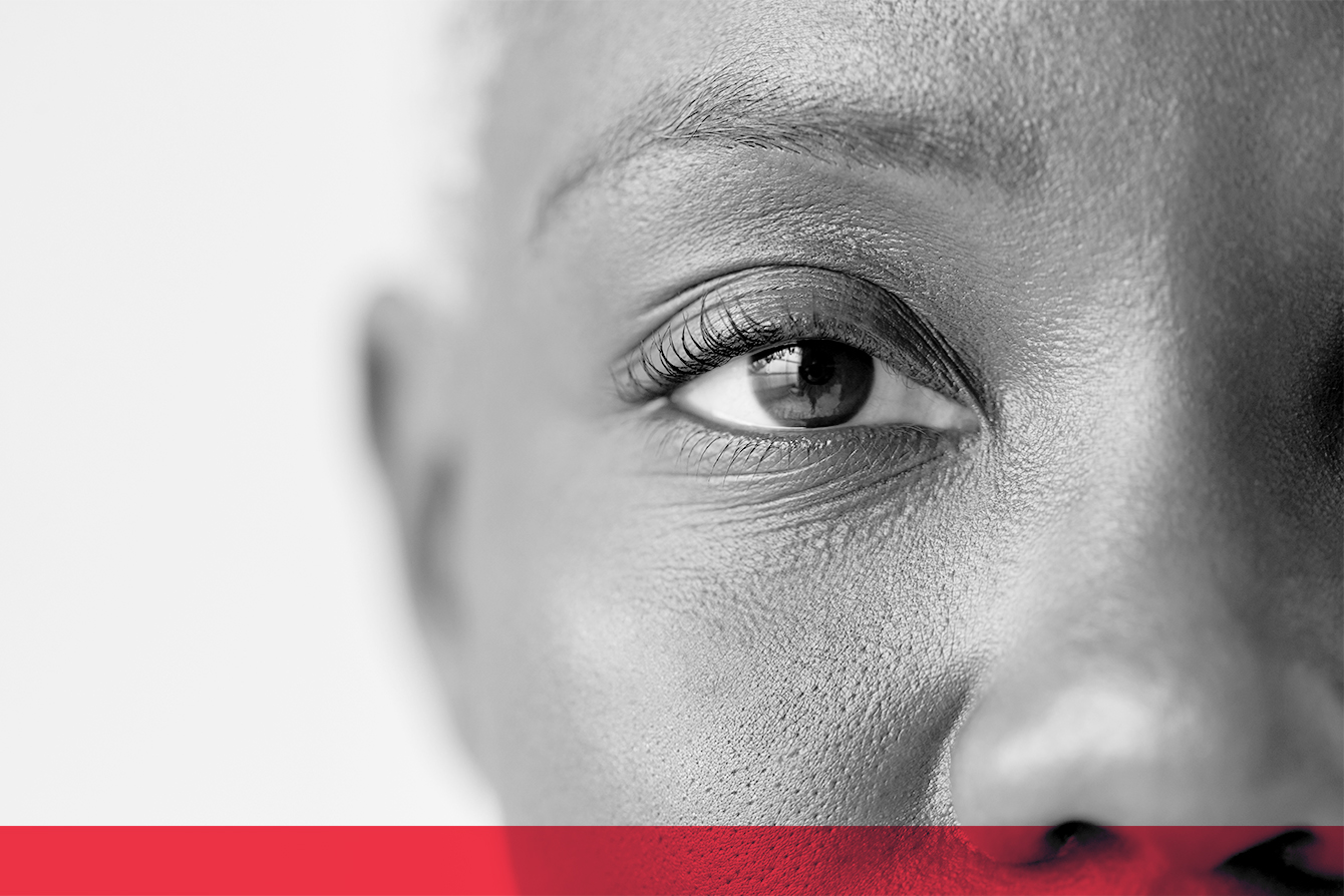 Close-up of a person's eye in black and white, with a red band across the bottom of the image.
