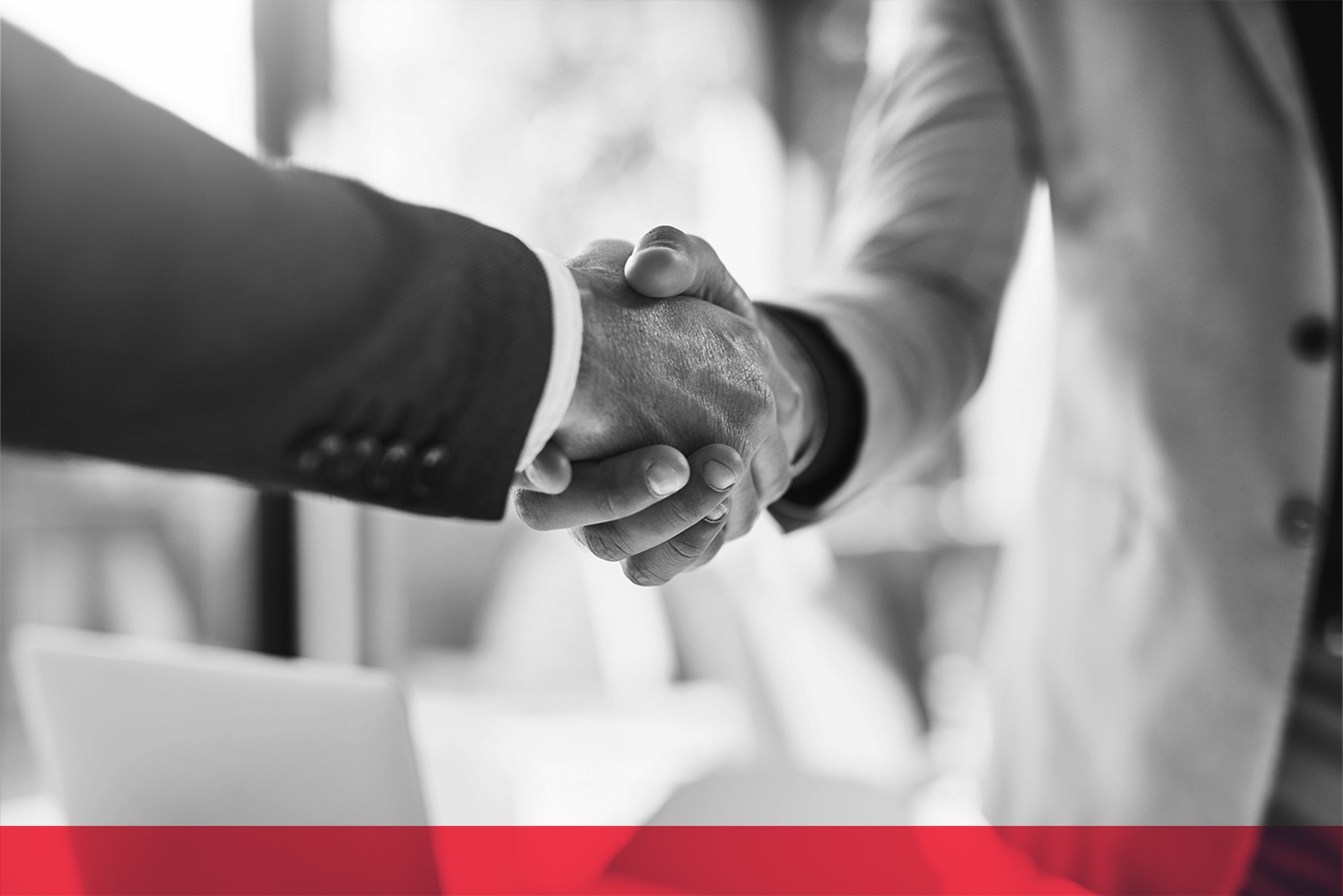 Black-and-white close-up of two people in business attire shaking hands.